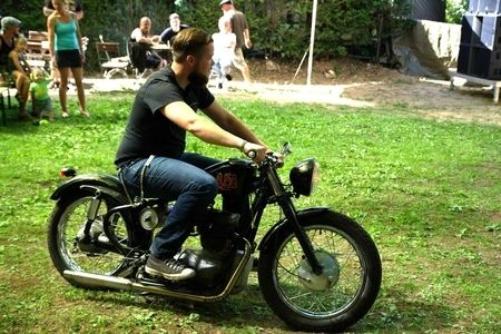 Biker mit seinem Motorrad auf einer grünen Wiese bei der 20 Jahres Feier der Biker-Schmiede in Berlin