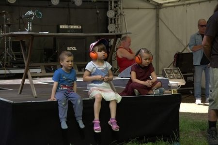 Drei Kinder mit Gehörschutz sitzen auf einer Bühne