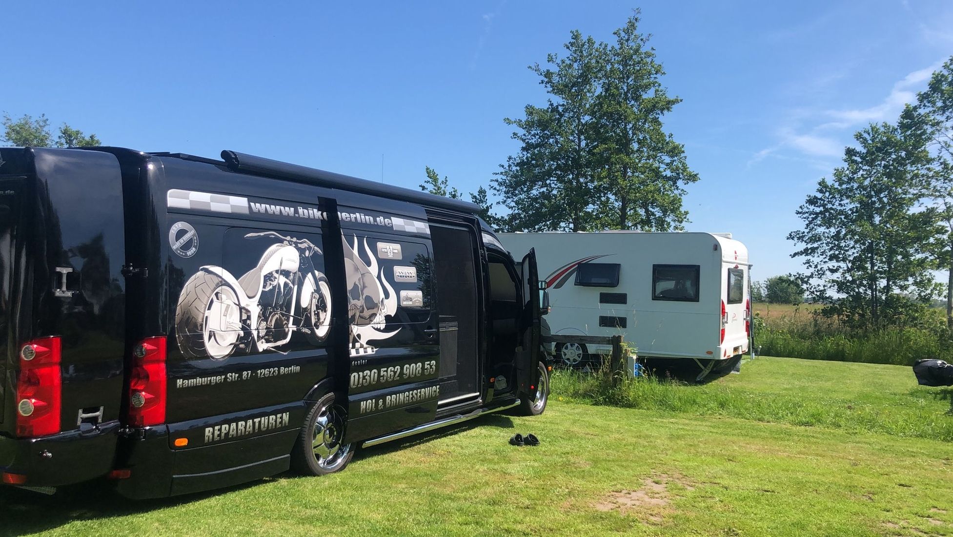 Zwei Camper-Fahrzeuge auf einer grünen Wiese unter blauem Himmel